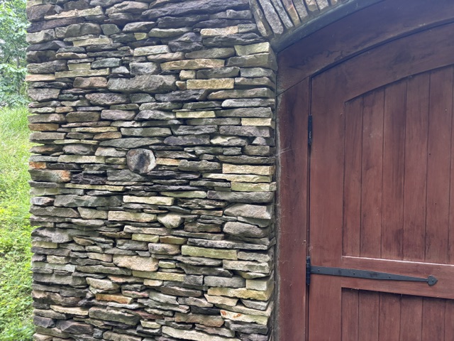 Dry-stack stone masonry wall with wooden door